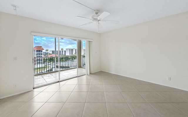 spare room with ceiling fan, a water view, and light tile patterned floors