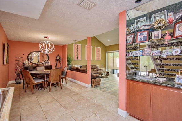 tiled dining space featuring a textured ceiling, sink, vaulted ceiling, and a notable chandelier