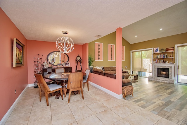 dining room with light hardwood / wood-style floors, vaulted ceiling, a textured ceiling, and a chandelier