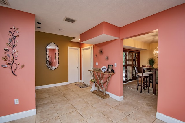 entrance foyer featuring light tile patterned floors, a textured ceiling, and an inviting chandelier