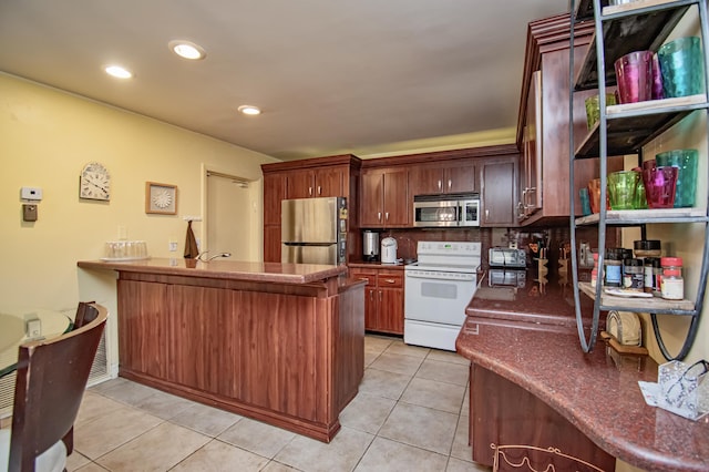 kitchen with kitchen peninsula, light tile patterned floors, backsplash, and appliances with stainless steel finishes