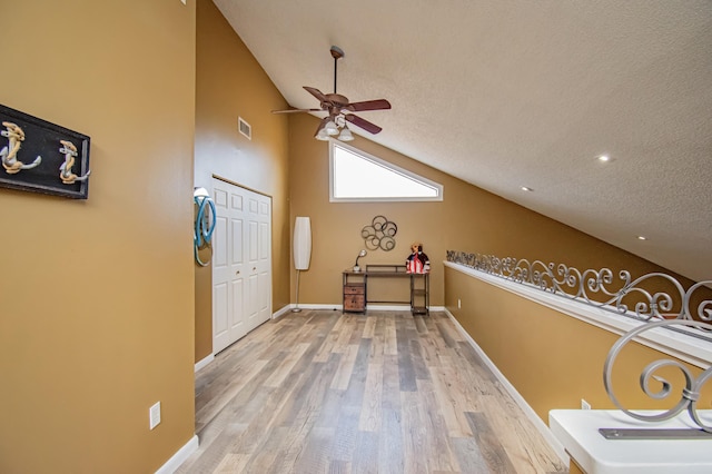 bonus room featuring a textured ceiling, hardwood / wood-style flooring, high vaulted ceiling, and ceiling fan