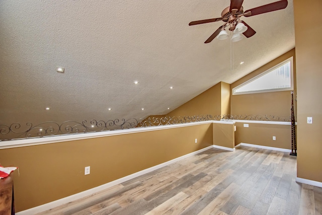 additional living space featuring vaulted ceiling, ceiling fan, wood-type flooring, and a textured ceiling