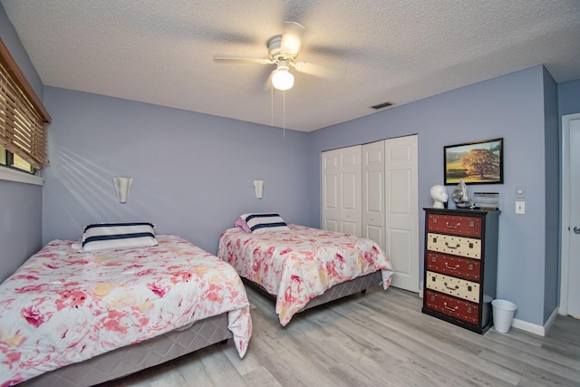 bedroom featuring ceiling fan, light hardwood / wood-style floors, a textured ceiling, and a closet