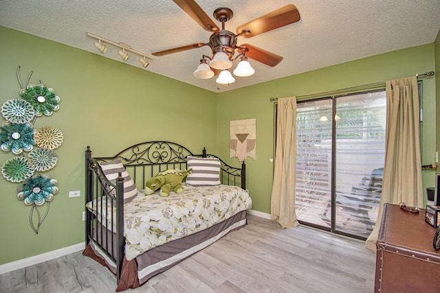 bedroom with access to exterior, a textured ceiling, light wood-type flooring, and ceiling fan