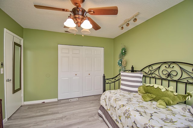 bedroom featuring ceiling fan, a closet, light hardwood / wood-style floors, and a textured ceiling