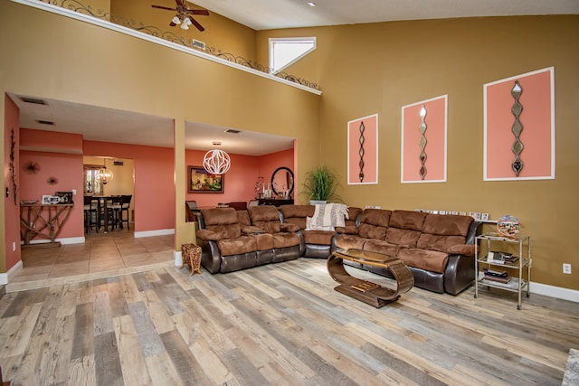 living room featuring ceiling fan with notable chandelier, wood-type flooring, and high vaulted ceiling