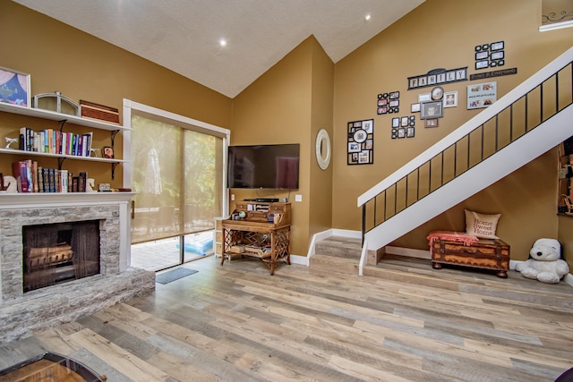 living room featuring a fireplace, light hardwood / wood-style floors, and high vaulted ceiling