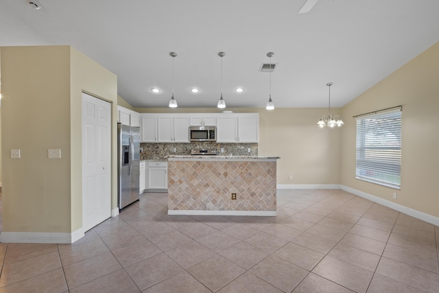 kitchen featuring lofted ceiling, decorative light fixtures, light tile patterned flooring, appliances with stainless steel finishes, and white cabinets