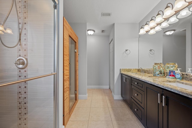 bathroom with a shower with door, vanity, and tile patterned flooring