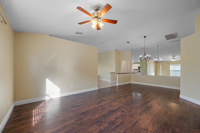 empty room featuring vaulted ceiling, dark hardwood / wood-style floors, and ceiling fan with notable chandelier