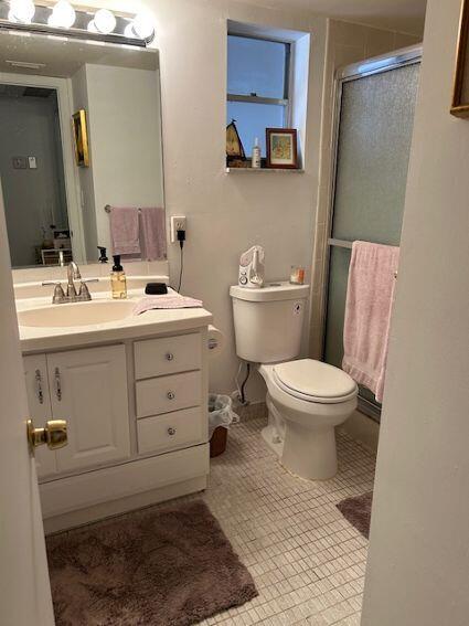 bathroom featuring tile patterned floors, vanity, toilet, and walk in shower