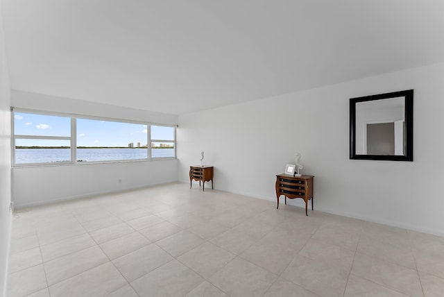 spare room with light tile patterned floors and a water view