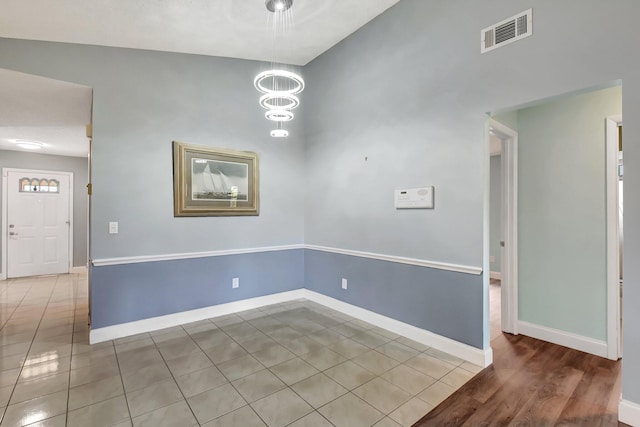 unfurnished room with hardwood / wood-style flooring, an inviting chandelier, and lofted ceiling