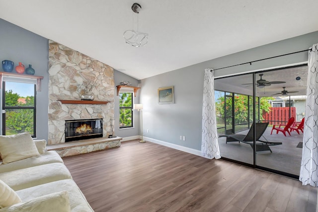 living room with hardwood / wood-style flooring, ceiling fan, a stone fireplace, and lofted ceiling