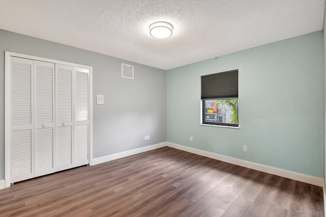 unfurnished bedroom with a closet, wood-type flooring, and a textured ceiling