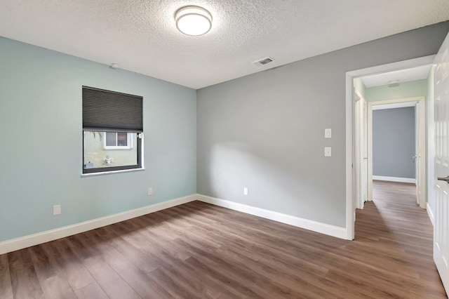 unfurnished room with hardwood / wood-style flooring and a textured ceiling