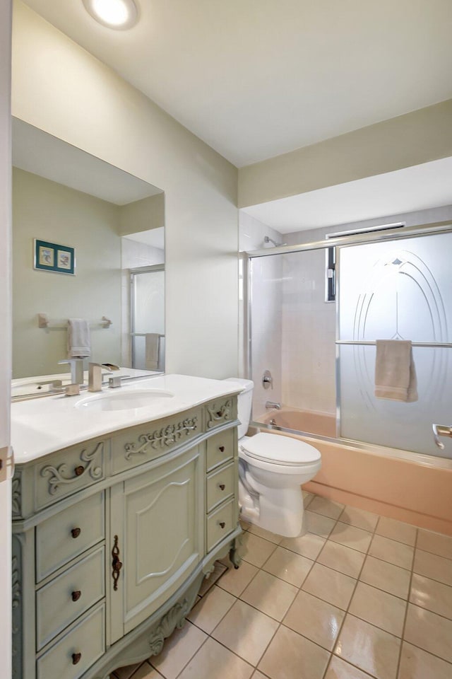 full bathroom featuring tile patterned floors, vanity, enclosed tub / shower combo, and toilet