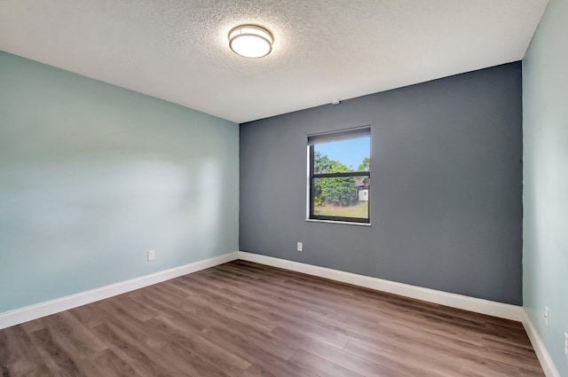 empty room with wood-type flooring and a textured ceiling