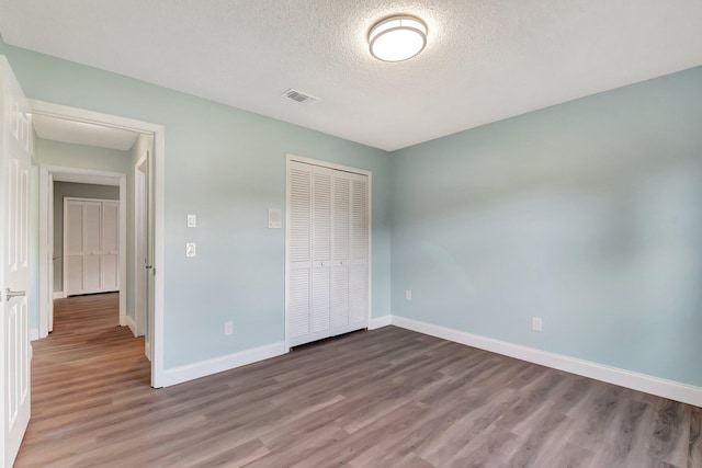 unfurnished bedroom featuring a closet, a textured ceiling, and hardwood / wood-style flooring