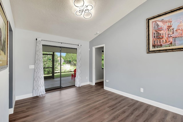 empty room featuring a textured ceiling, dark wood-type flooring, and vaulted ceiling