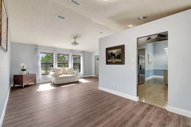 unfurnished living room with ceiling fan, wood-type flooring, and a textured ceiling