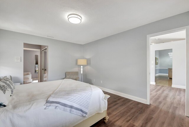 bedroom with wood-type flooring and ensuite bath