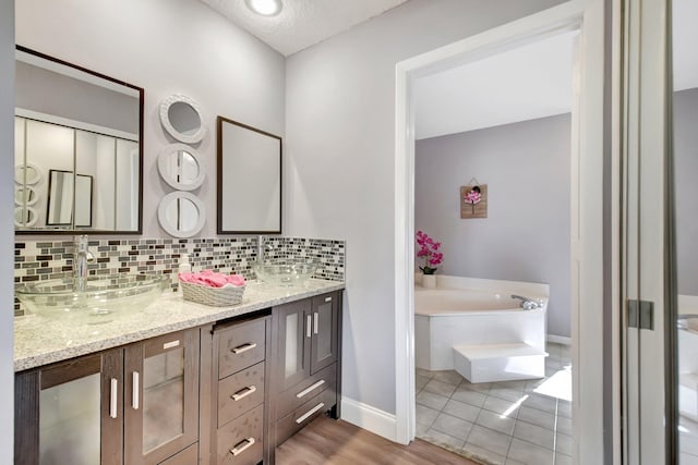 bathroom with backsplash, a washtub, vanity, a textured ceiling, and wood-type flooring