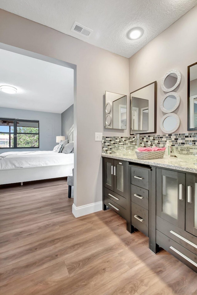 bathroom with wood-type flooring, vanity, tasteful backsplash, and a textured ceiling