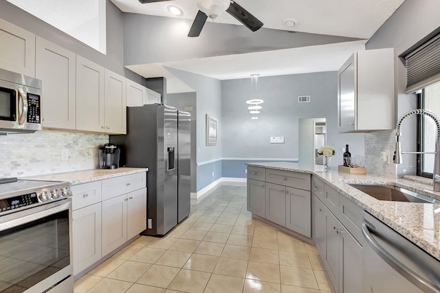 kitchen with light stone countertops, appliances with stainless steel finishes, tasteful backsplash, and sink