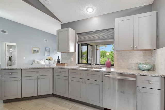 kitchen with gray cabinetry, sink, stainless steel dishwasher, vaulted ceiling, and decorative backsplash