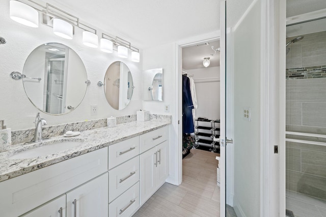 bathroom featuring vanity, a shower with shower door, and a textured ceiling