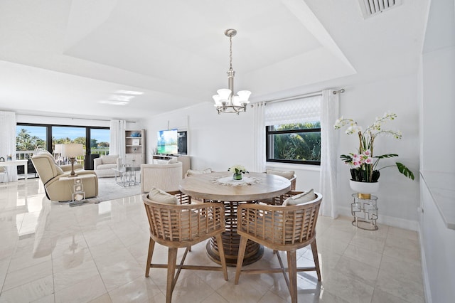 dining room with a tray ceiling and a notable chandelier