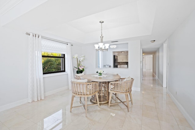 tiled dining space with a raised ceiling and an inviting chandelier