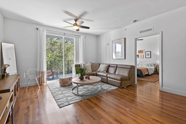 living room featuring ceiling fan, wood-type flooring, and a textured ceiling