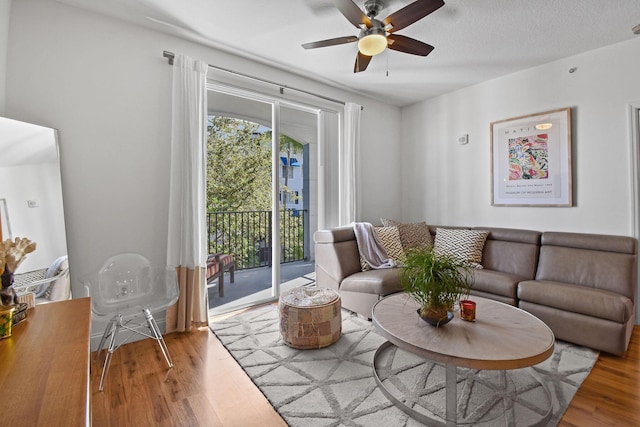 living room with ceiling fan, light wood-type flooring, and a textured ceiling