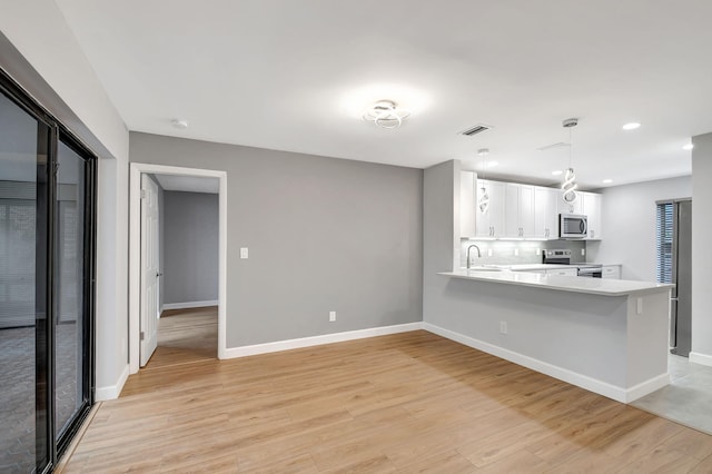 kitchen featuring white cabinetry, kitchen peninsula, stainless steel appliances, and light hardwood / wood-style flooring