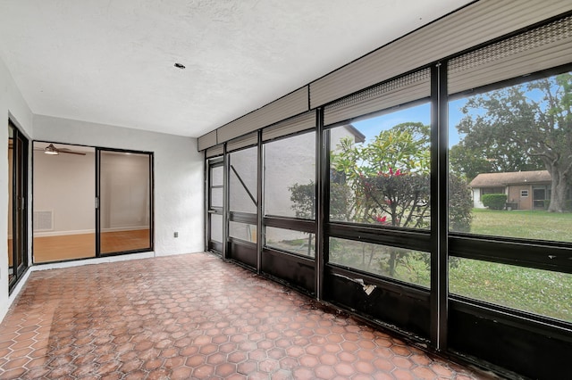 unfurnished sunroom featuring ceiling fan