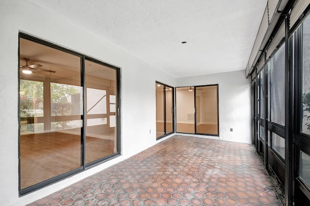 unfurnished sunroom featuring ceiling fan