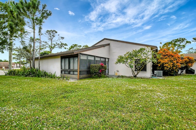 back of property featuring a sunroom, cooling unit, and a lawn