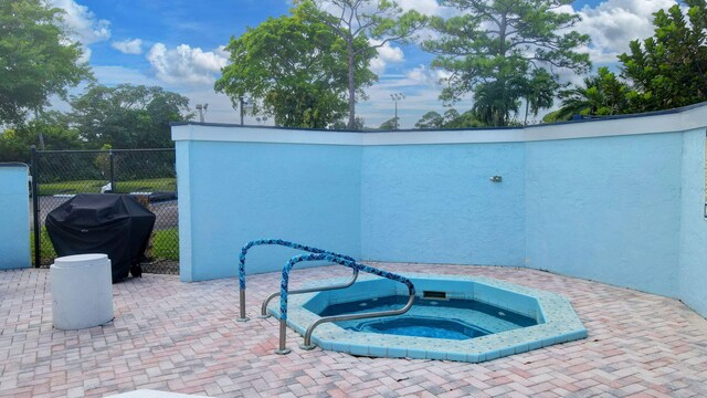 view of pool with an in ground hot tub, area for grilling, and a patio area