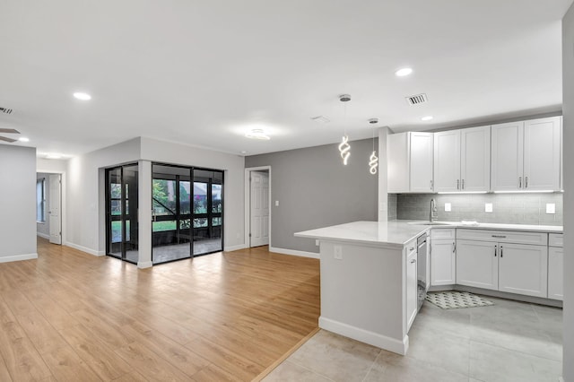 kitchen featuring white cabinetry, kitchen peninsula, hanging light fixtures, and light hardwood / wood-style flooring