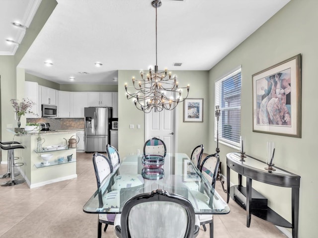 dining room with a chandelier, ornamental molding, and light tile patterned flooring