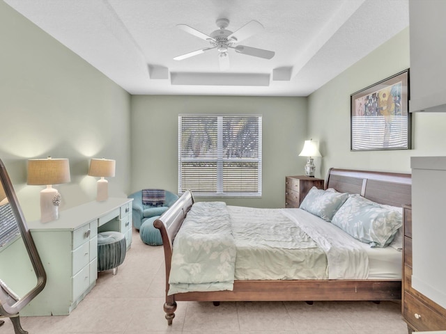 tiled bedroom featuring a raised ceiling, ceiling fan, and a textured ceiling