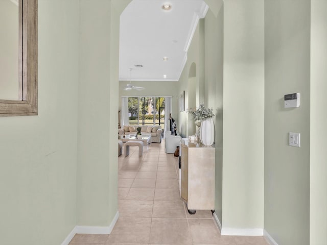 corridor featuring light tile patterned floors and ornamental molding