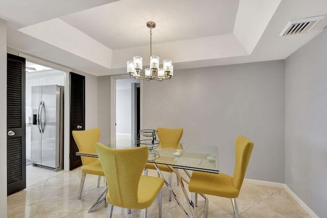 tiled dining room with a tray ceiling and an inviting chandelier