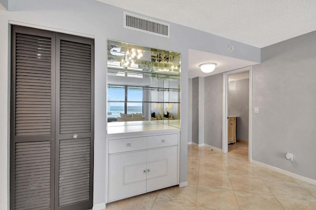 interior space featuring white cabinetry, a textured ceiling, and light tile patterned floors