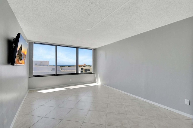 tiled empty room featuring a textured ceiling