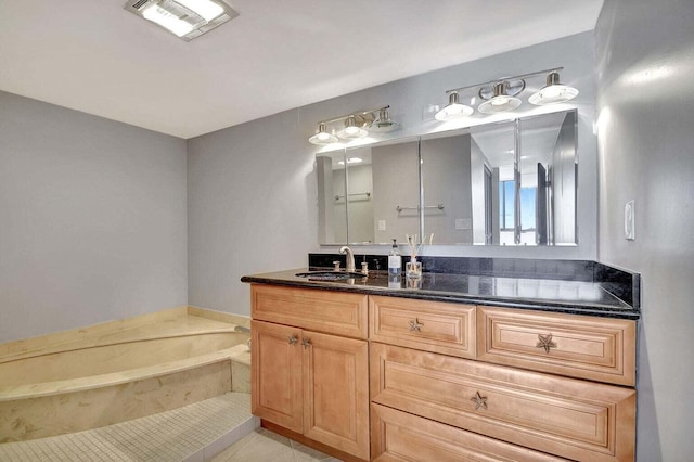 bathroom with a tub to relax in, tile patterned flooring, and vanity