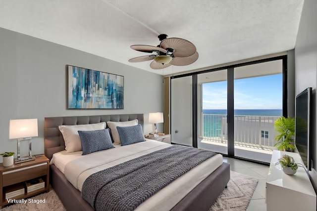 tiled bedroom featuring ceiling fan, expansive windows, and access to exterior